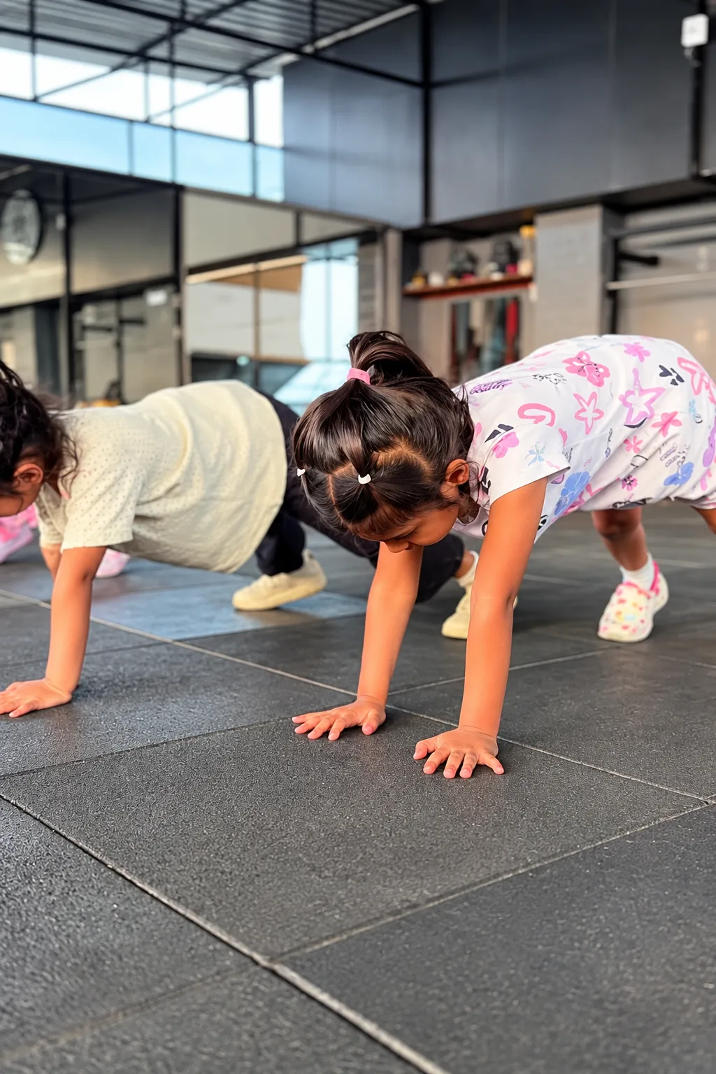 Young children holding plank position on a gym floor