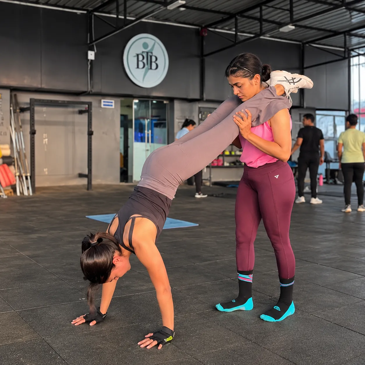 Coach assisting a member through an inverted stretch at the BTB gym